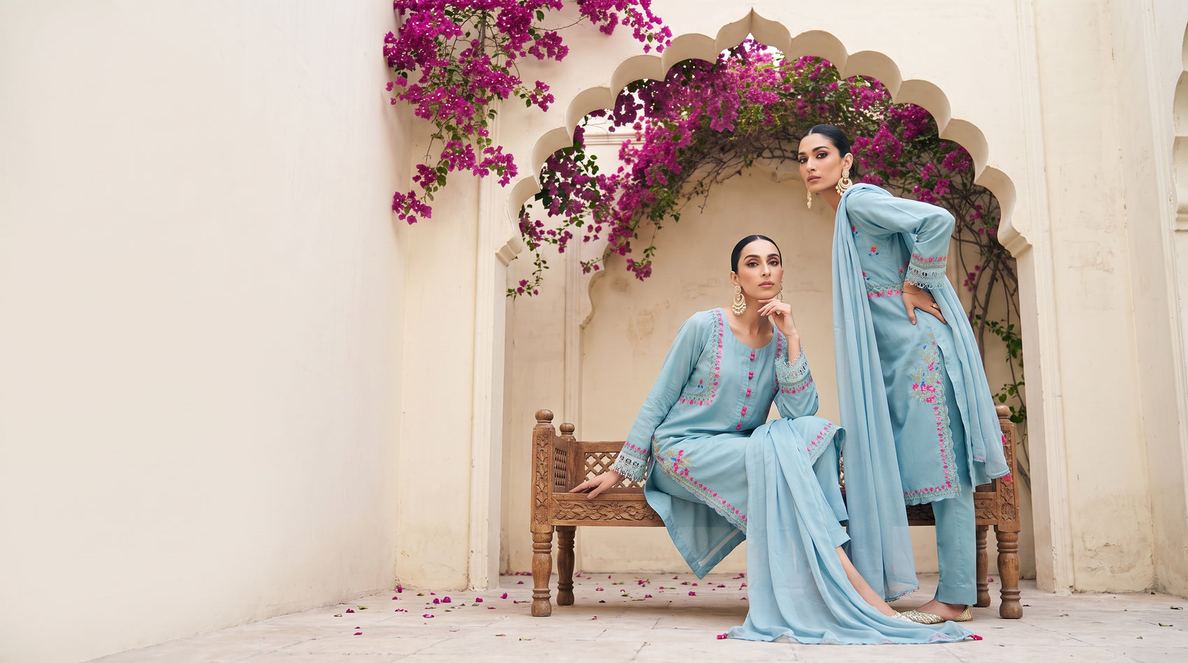 Two models in the powder blue embroidered kurta set under a bougainvillea archway