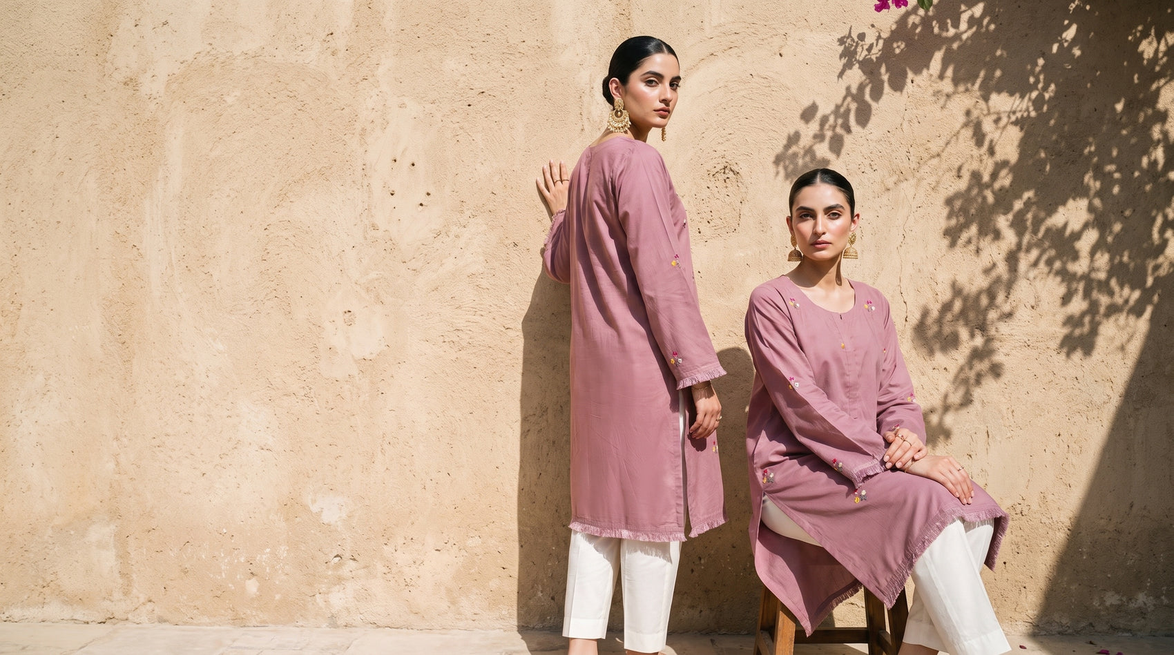 Two models in the dusty rose kurta set against a sunlit stucco wall with bougainvillea shadows