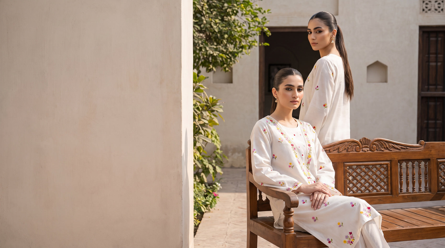 Two models in the white multicolour embroidered kurta set in a haveli courtyard